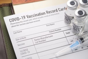 Covid 19 vaccination record card with vials and syringe. 1289454645 1257x838